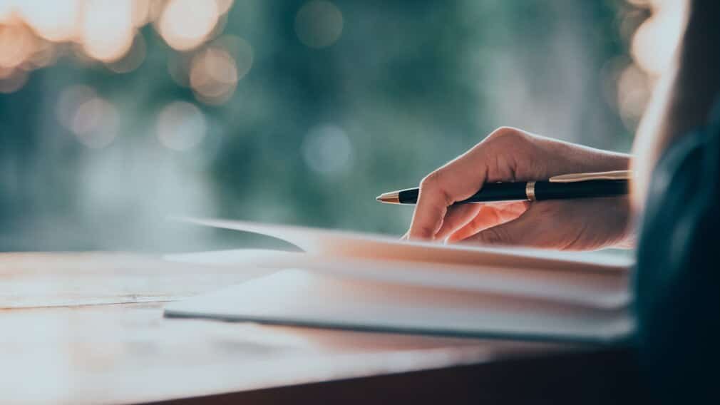 Person sitting at desk writing in journal