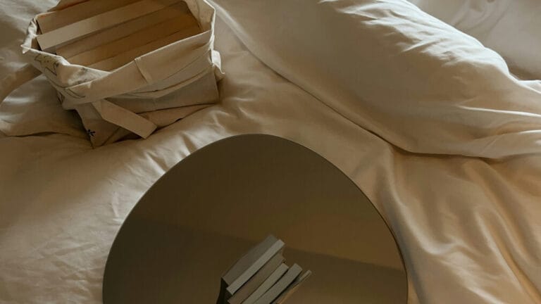 Books and mirror resting on bed