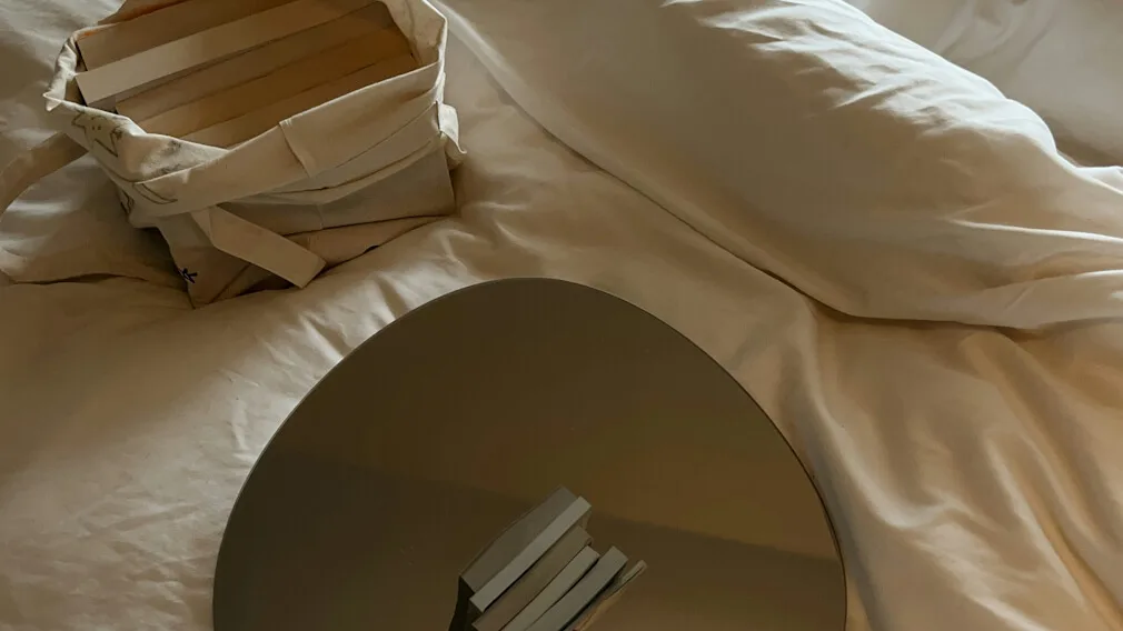 Books and mirror resting on bed