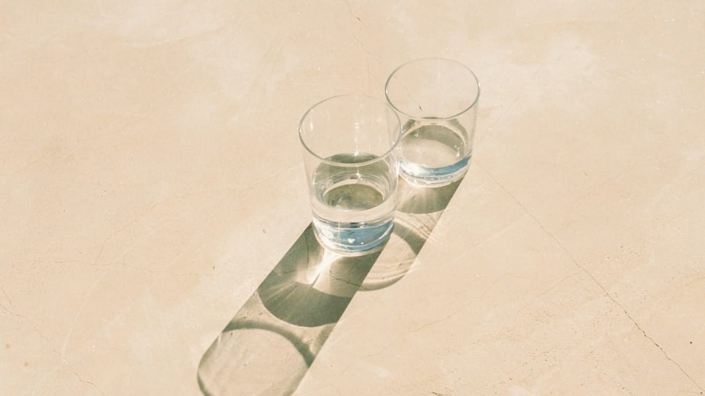 Two glasses of water sitting on a wall