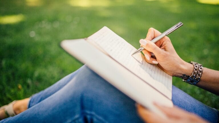 Sitting on grass and writing in a journal