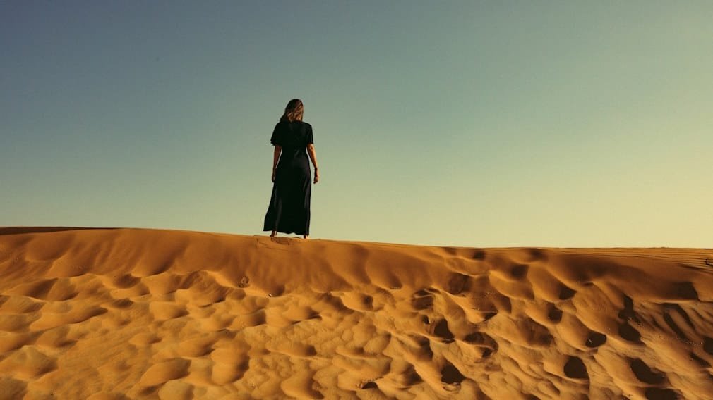 Woman standing at the top of a sand dune